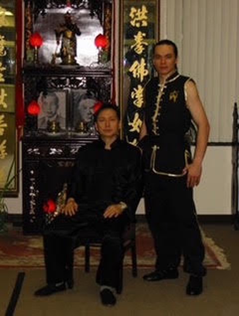 Grandmaster Sifu Tai Yim seated beside a master promoted after the first group of 9th-generation masters, before the school altar